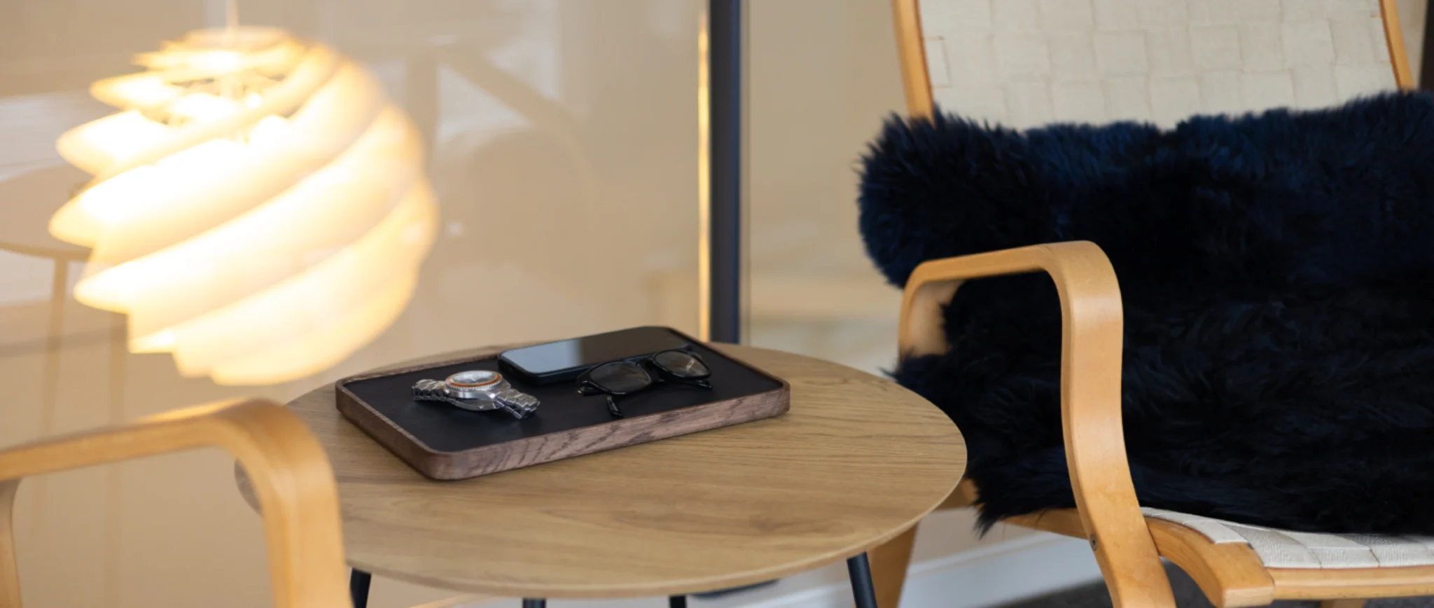 Signaturbakke i mørk eg på sofabord med telefon og briller lagt fra sig